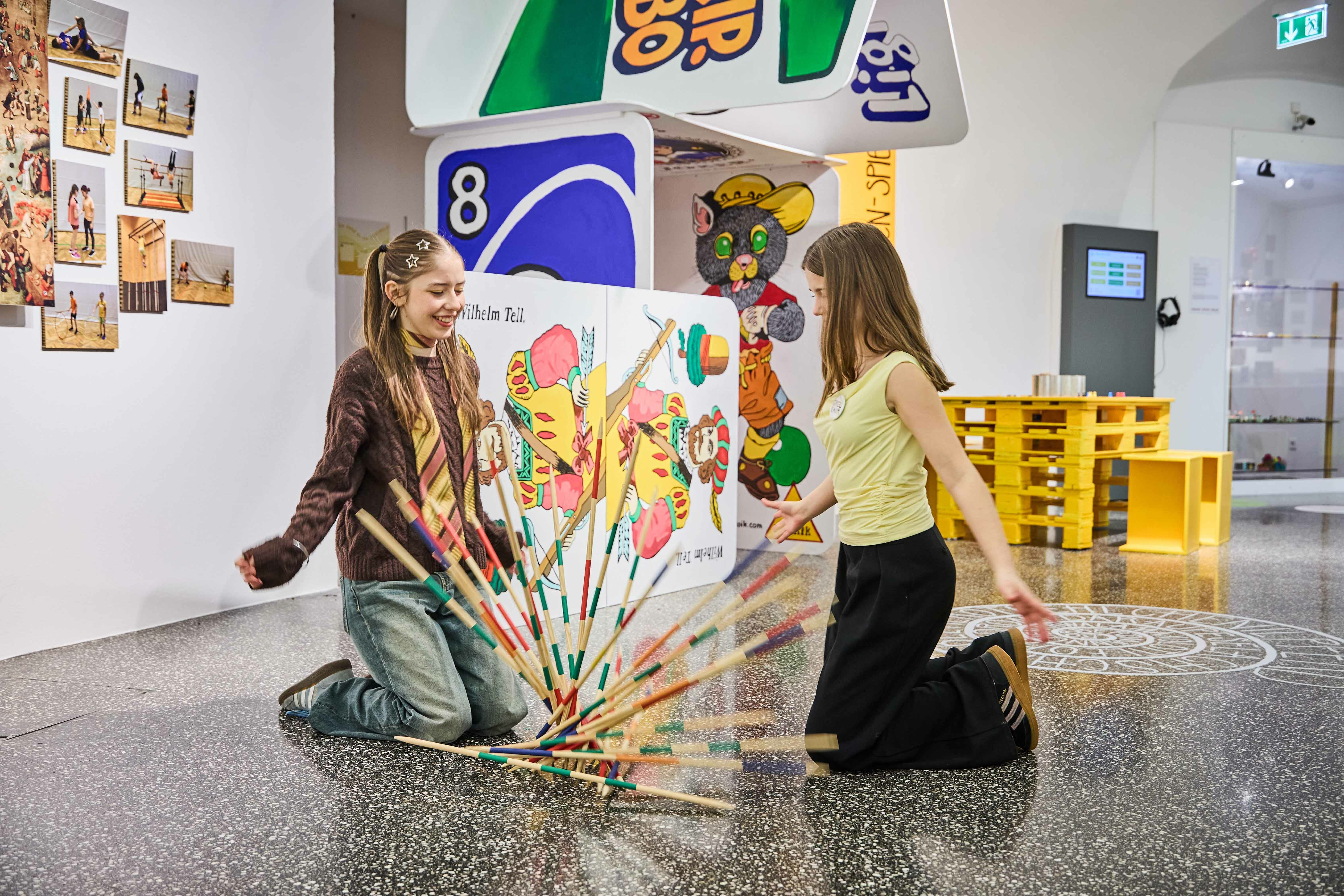 Jugendliche mit Mikadostäben und Spielkarten in Übergröße Jugendliche mit Mikadostäben und Spielkarten in Übergröße